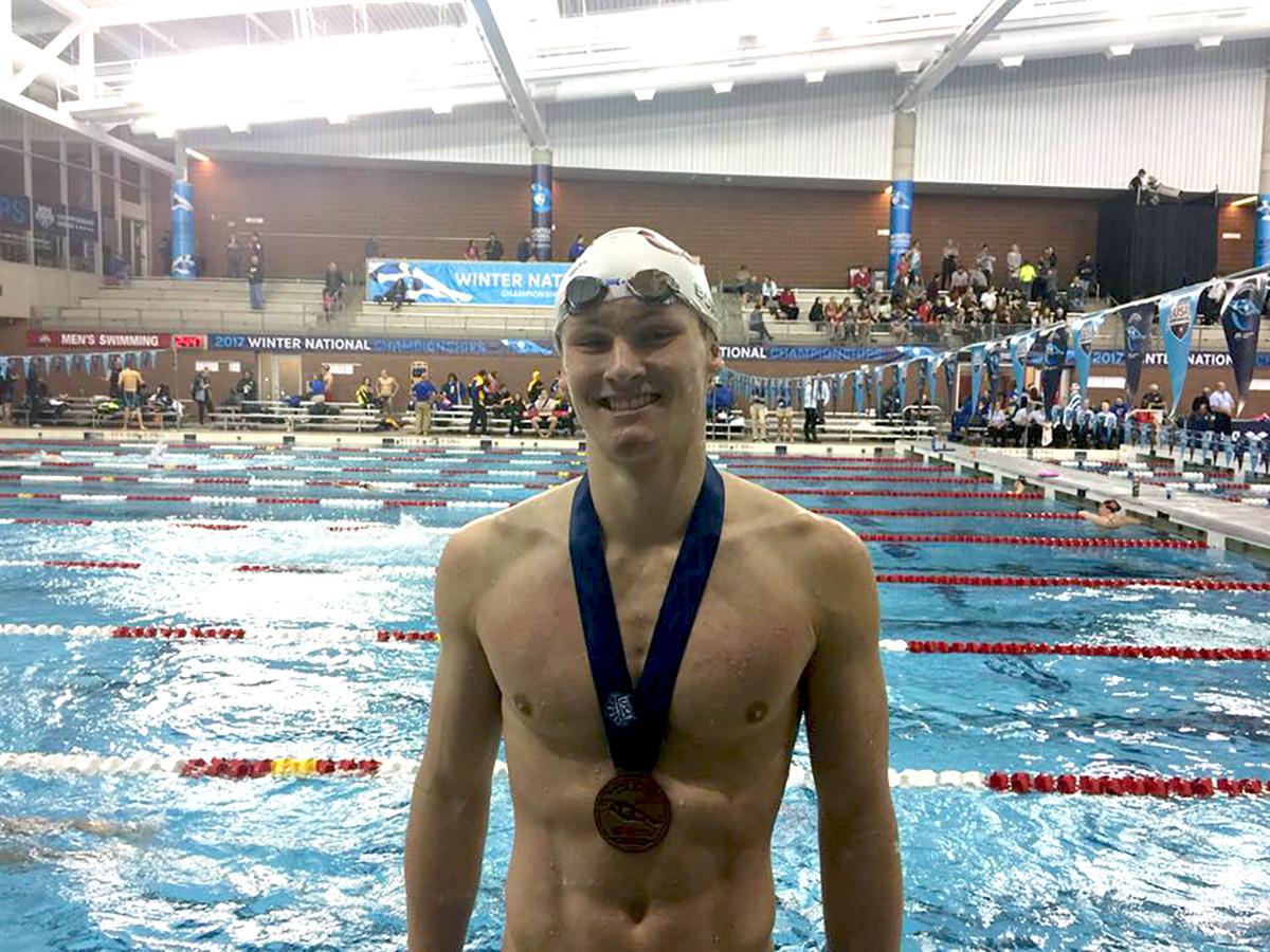Upper Main Line YMCA Swim Team member Brendan Burns poses at the end of a swim meet where he won a medal for swimming. 
