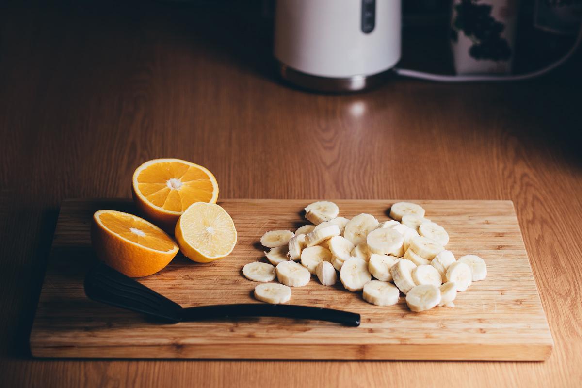 A cutting board with an orange and banana to make a healthy meal. 