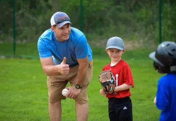 Youth Sports - A volunteer baseball coach gives the thumbs up to his player during a tball game at the YMCA in Chester County.