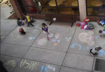 Students at the Oscar Lasko YMCA using sidewalk chalk outside on a nice spring day.