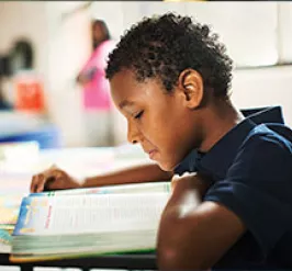 Young boy reading a book at the YMCA of Greater Brandywine. 