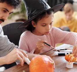 A father and daughter paint pumpkins at a halloween event for families at the YMCA in Exton, pa