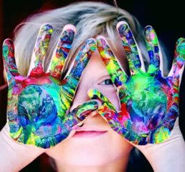 Young child with colorful paint on their hands. 