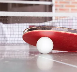 Ping pong paddle and ball on ping pong table. 