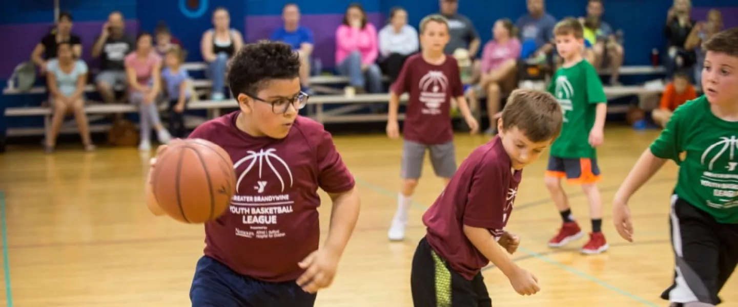 Youth basketball player dribbling a basketball during a YMCA youth sport league game.