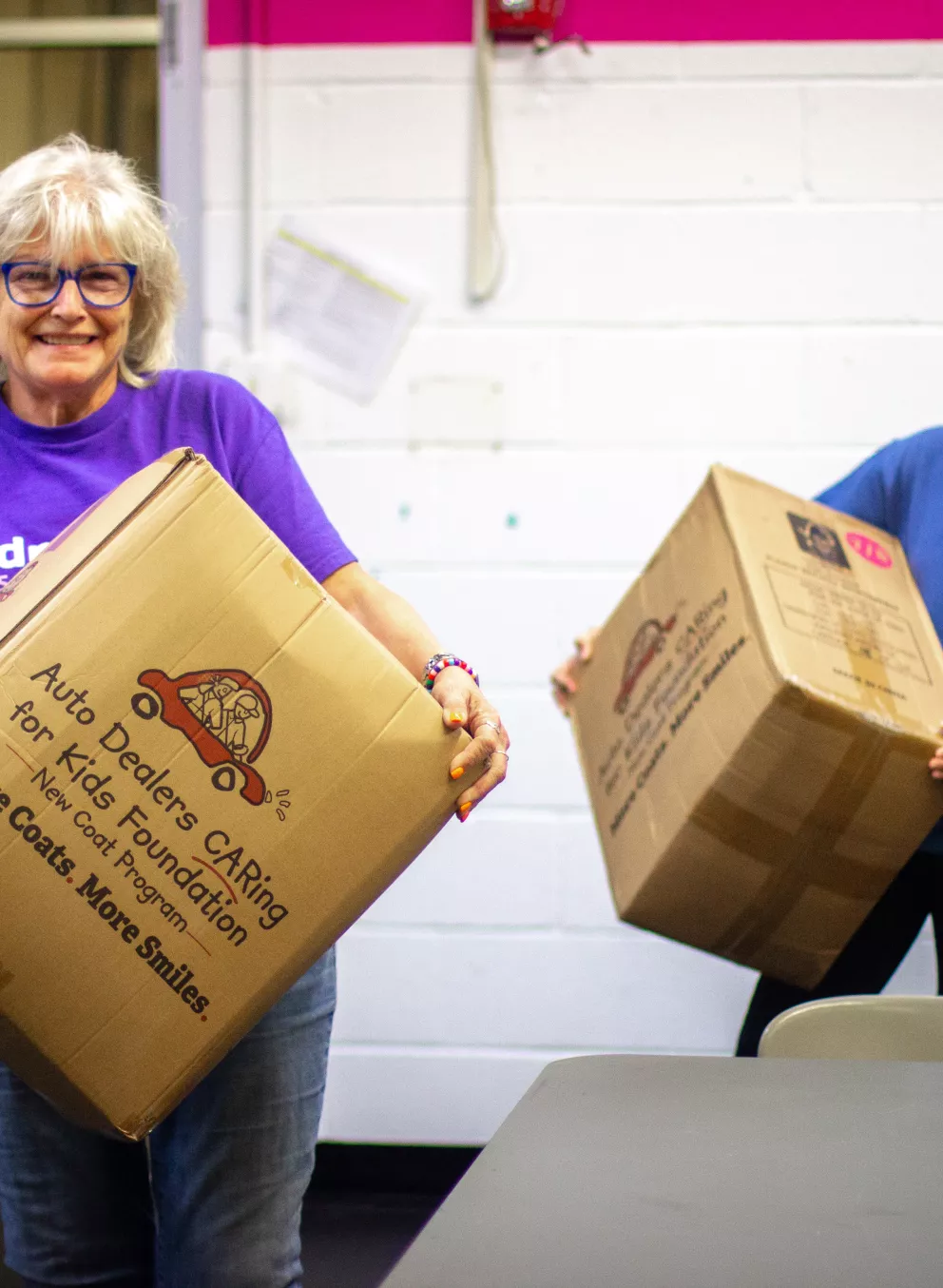 Two staff  members of the YMCA of Greater Brandywine bringing in coats to be donated to local children.