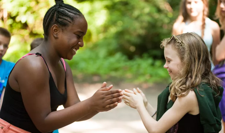Two kids participate in a clapping game during their day at summer camp. 