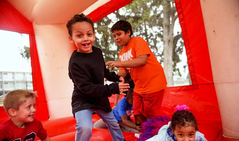 A group of kids play in a bounce house at a YMCA Healthy Kids Day event. 
