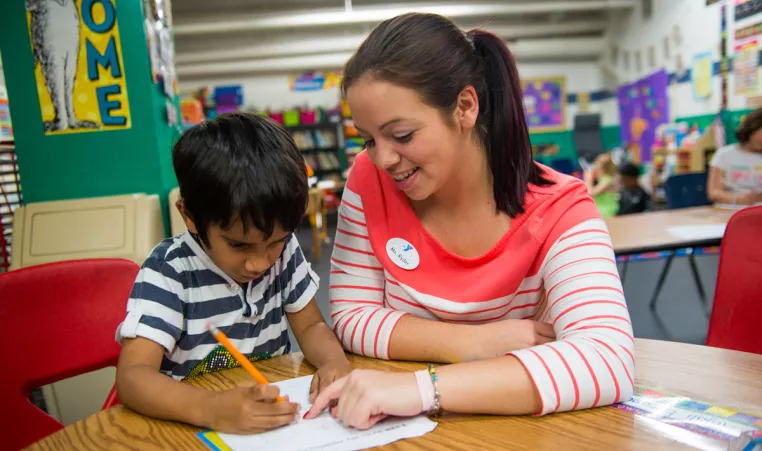 Kindergarten teacher helping a student with homework at the Oscar Lasko YMCA in West Chester, Pa
