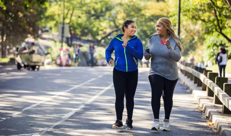 Two women participating in the YMCA Healthy Weight Loss program take a walk outside. 
