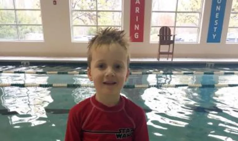Dean, a young boy, poses at the indoor swimming pool at the West Chester Area YMCA where he learned how to swim. 