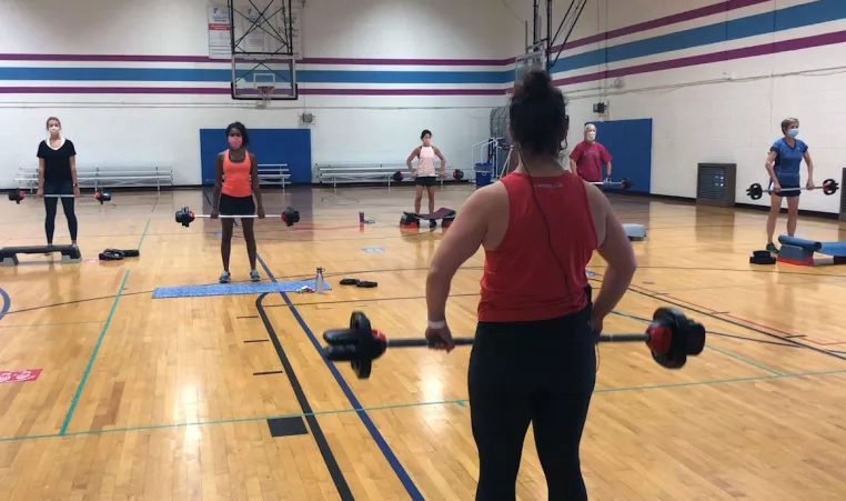 Clarie, a group exercise instructor, holds a weight while teaching a group exercise bodypump class post-COVID at the Upper Maine Line YMCA gymnasium in Berwyn, PA.