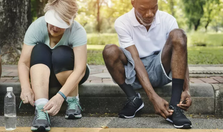 two senior adults lace their sneakers before exercising