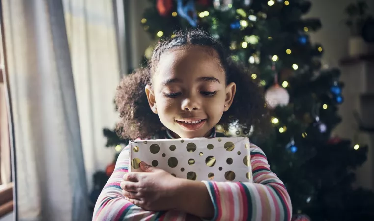 Smiling child hugging a holiday gift