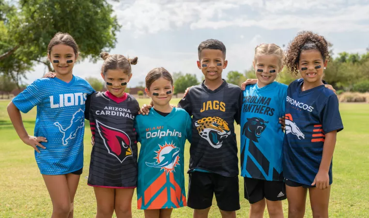 Youth NFL flag football athletes pose for a photo on the outdoor athletic fields at the YMCA