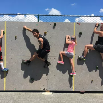 A family climbs the rock wall at the CAN outdoor training facility at the Brandywine YMCA