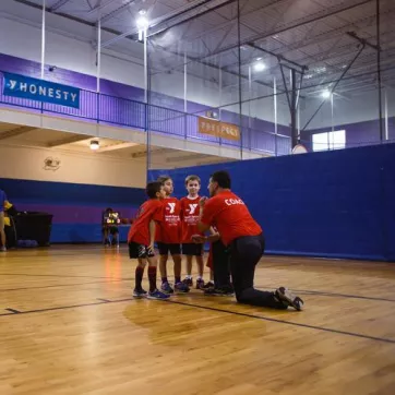 Youth Sports - A youth basketball team huddles up with their volunteer coach before the start of the basketball game at Kennett YMCA in Kennett Square, PA.