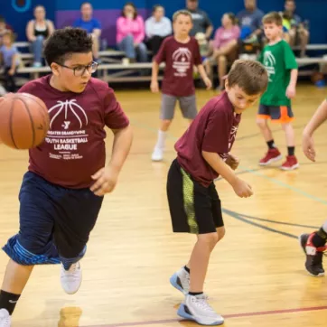 Youth basketball player dribbling a basketball during a YMCA youth sport league game. 