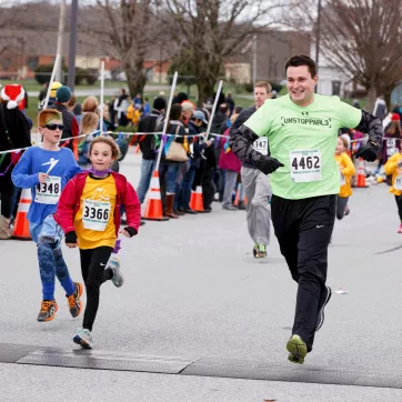 A STRIDE and Girls on the Run participant crosses the finish line for the 5K with their running buddy.