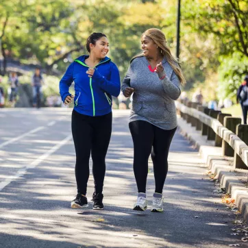 Two women participating in the YMCA Healthy Weight Loss program take a walk outside. 