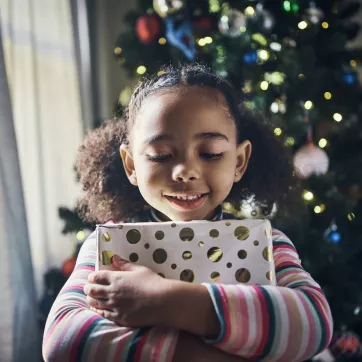 Smiling child hugging a holiday gift