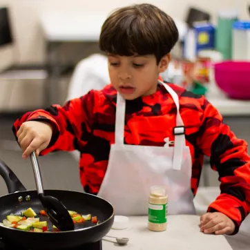 child cooking vegetables
