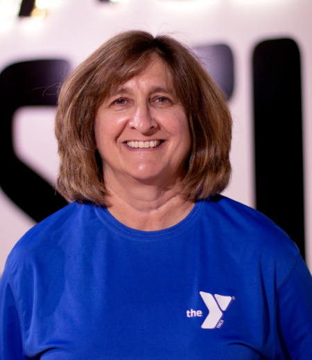 Personal Trainer stands in front of a Y logo while smiling